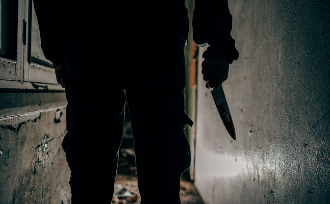 Das Bild zeigt eine Person bei Dunkelheit, die ein Messer in der Hand hält.